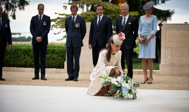 Kate Middleton coloca flores sobre o memorial aos ex-combatentes da Primeira Guerra no cemitério St Symphorien, na Bélgica, acompanhada do marido, príncipe William, do primeiro-ministro inglês David Cameron e do cunhado, príncipe Harry (Paul Shaw / The Prime's Minister Office / Divulgação)