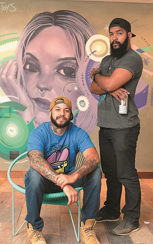 Os artistas Daniel Moraes e Mikael Guedes, conhecidos por Toys e Omik, em frente a um painel pintado para a Casa Cor Brasília: eles celebram a redução do preconceito em relação ao grafite (Raimundo Sampaio/Encontro/DA Press)