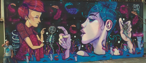 Criador e criatura: Thales Fernando, o Pomb, brinca ao lado do painel que pintou na rua (Arquivo pessoal)